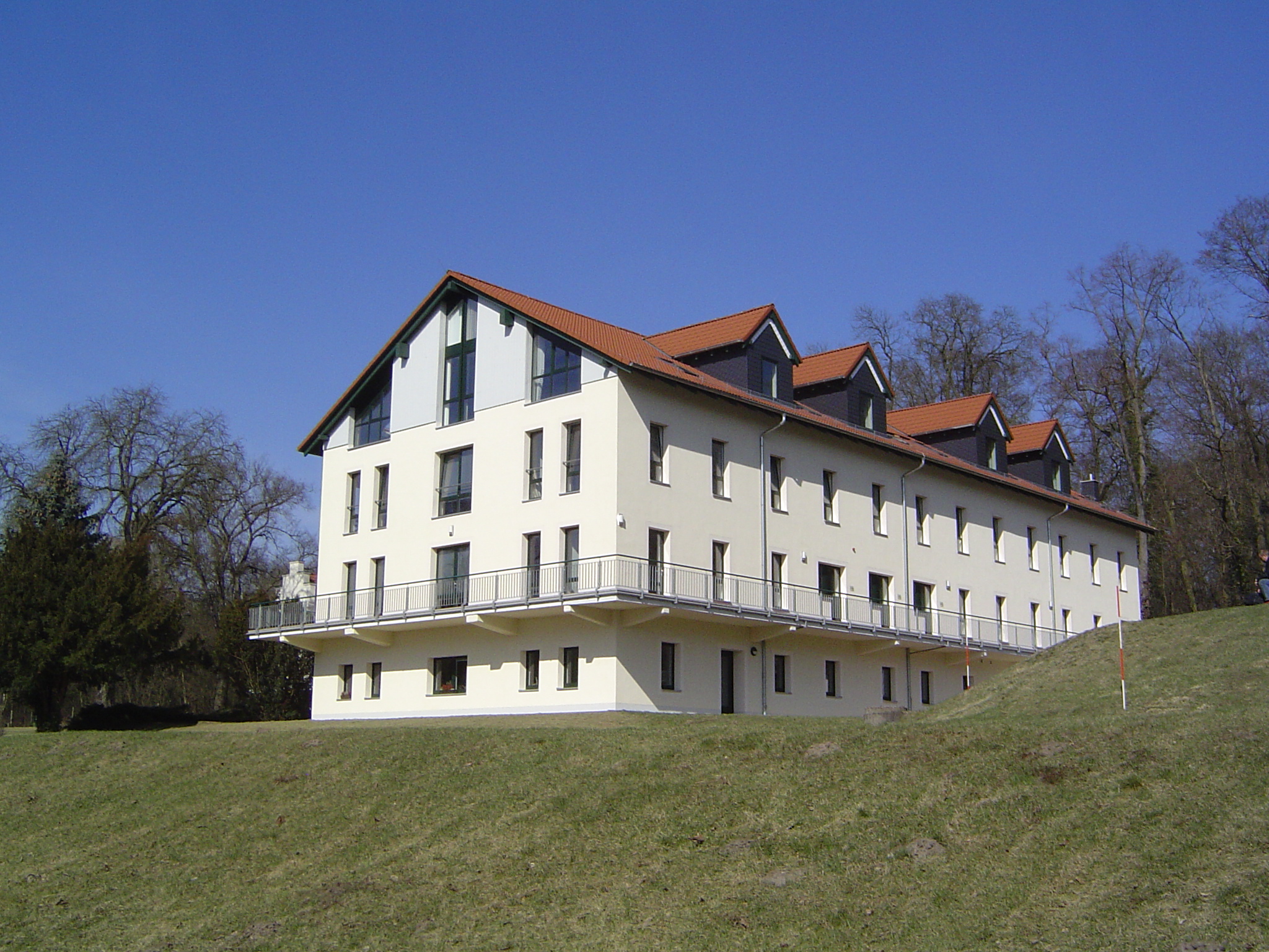 Weißes Gebäude mit Planungsbüro auf grüner Anhöhe
