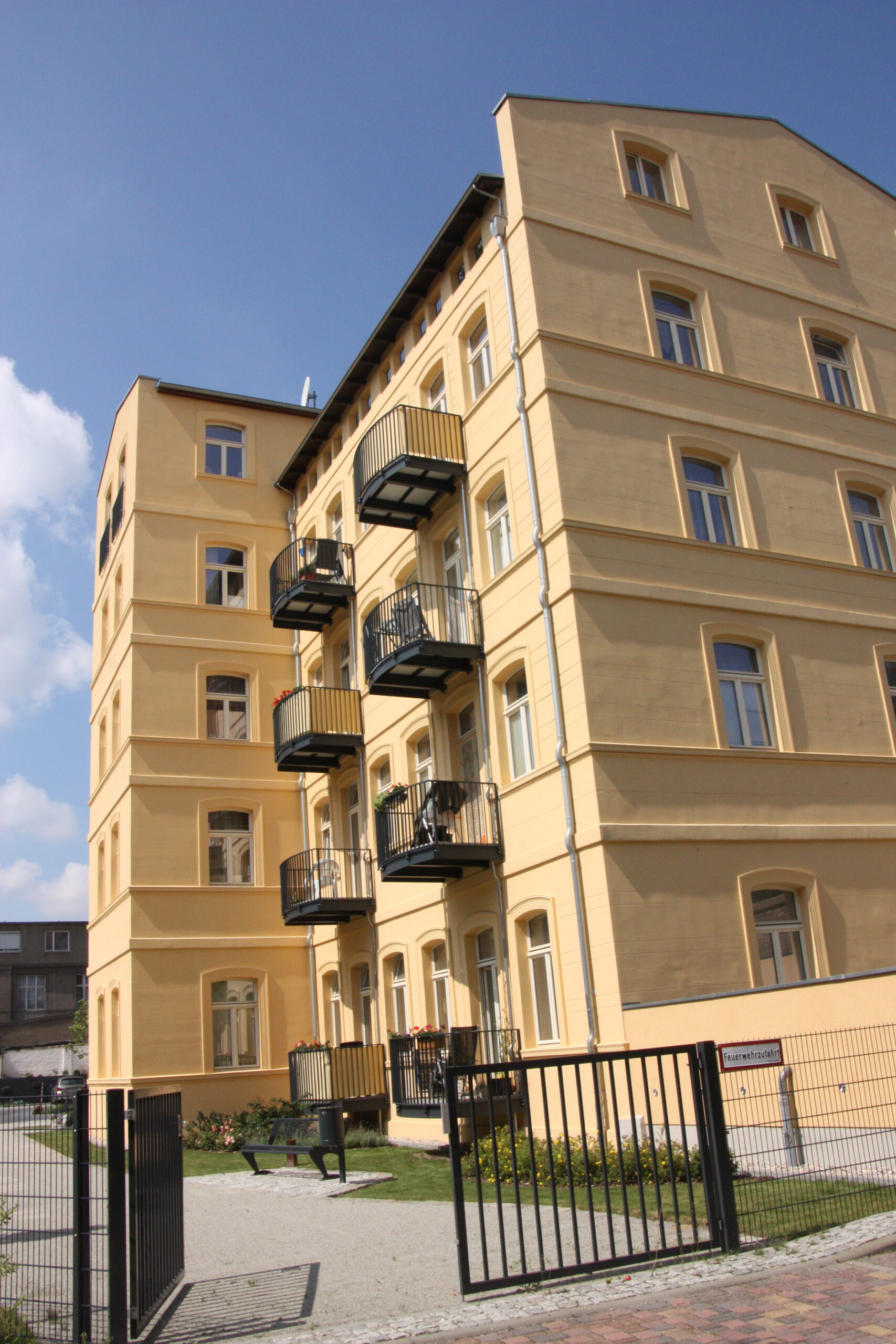 Gelbes Gebäude mit Balkonen, nahe einem Planungsbüro.