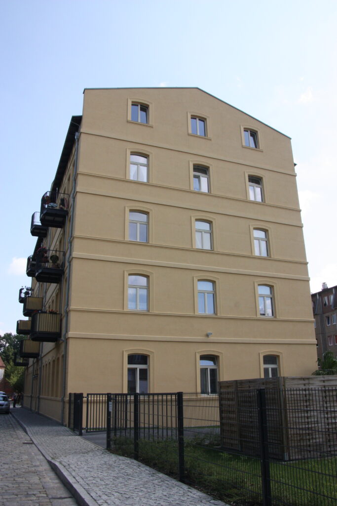 Gelbes Gebäude mit Balkonen, nahe einem Planungsbüro.